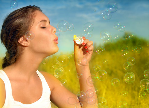 Summer fun, young woman blowing soap bubbles at sunset
