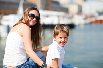 Fototapeta na wymiar Mother and son sitting on jetty in city center