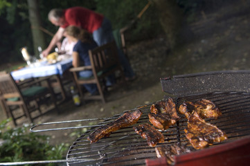 BBq with meat in foreground people in background