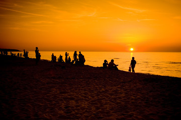 Ludzie obserwujący zachód słońca nad morzem bałtyckim - obrazy, fototapety, plakaty