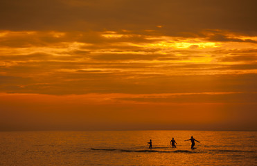 Rodzina kąpiąca się w morzu podczas zachodu słońca