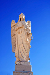 Marble angel statue with a bright blue sky in a cementry