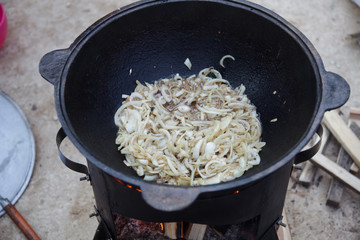 cooking pilaf in a cast iron cauldron over a fire