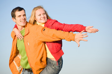 Young love couple smiling under blue sky
