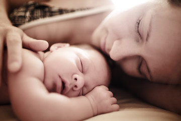 Newborn baby sleeping with mother. Closeup, shallow DOF.