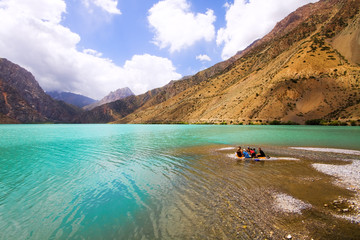 People on mountain lake under cloudy sky