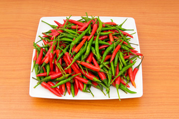 Hot peppers in the plate on wooden table