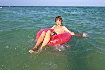 boy in a swim ring has fun in the ocean