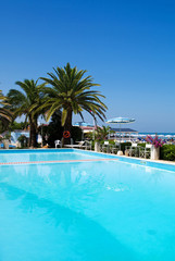 Fototapeta na wymiar Swimming pool with palms near the sea