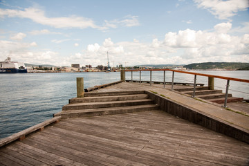 a quay with a wooden floor in a norwegian port in a beautiful summer day with some clouds in the blue sky