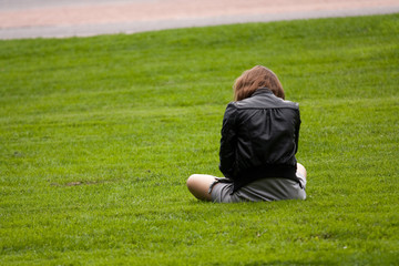 a girl alone with a beautiful skirt sitting in park on the grass thinking of her sadness