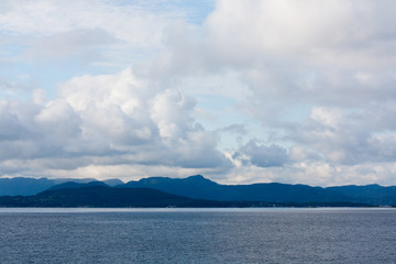 panorama with the sea, blue mountains and clouds with a blue sky in a mysterious summer day in Norway