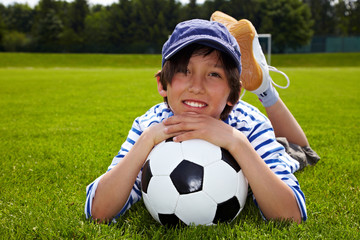 Junge liegt auf Fußball