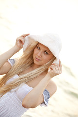 Beautiful young blonde girl in hat on the beach