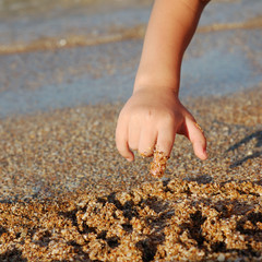 child drawing on sand