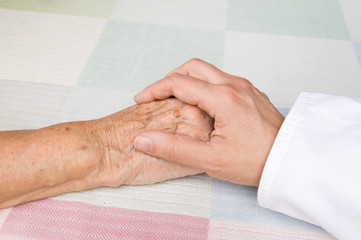 hand of a doctor holding the hand of an elderly patient