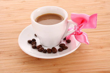 Small white cup of coffee with coffee grain on brown background