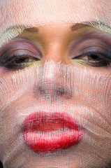 The woman's face with bright makeup veiled with gauze