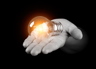 Hand holding light bulb isolated on black