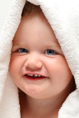 Cute baby girl smiling under a white towel after bath
