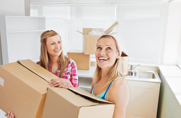 Two radiant women carrying boxes at home