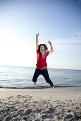 Obraz premium Beautiful brunet girl jumping on the beach.