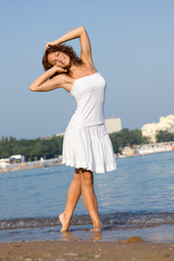 Young beautiful girl in a white dress on the beach