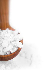 bath salt on a wooden spoon closeup on white background