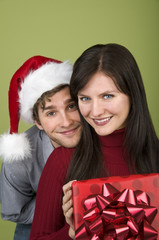 Man in Santa hat leaning on woman with gift