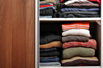 Open wardrobe with lots of folded clothes