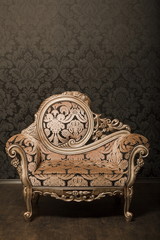 vintage brown-gray chair with gold accents standing beside wall