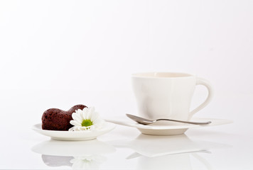 tea or coffee and heart shaped cookie with flower on a plate
