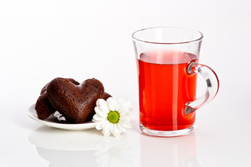 heart shaped cookie with flower on a plate and fruit tea in glas