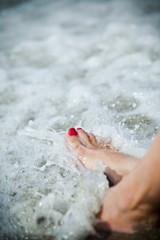 Fototapeta na wymiar Woman feet and water splashing - lonely day at the beach