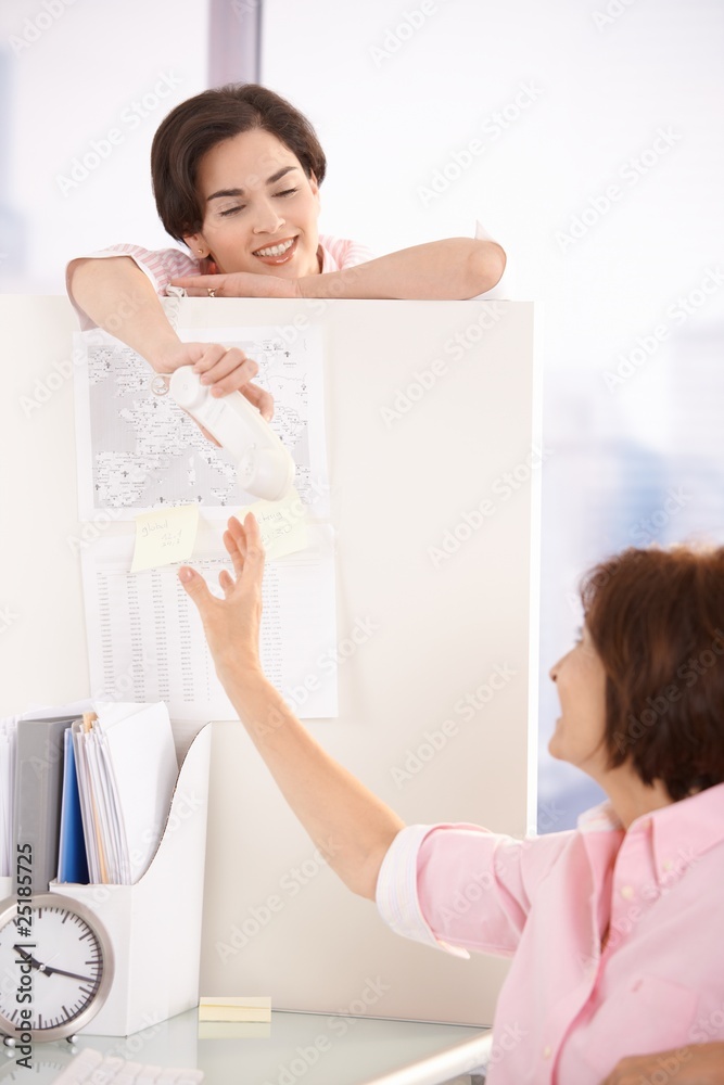 Poster colleague handing over phone to office worker