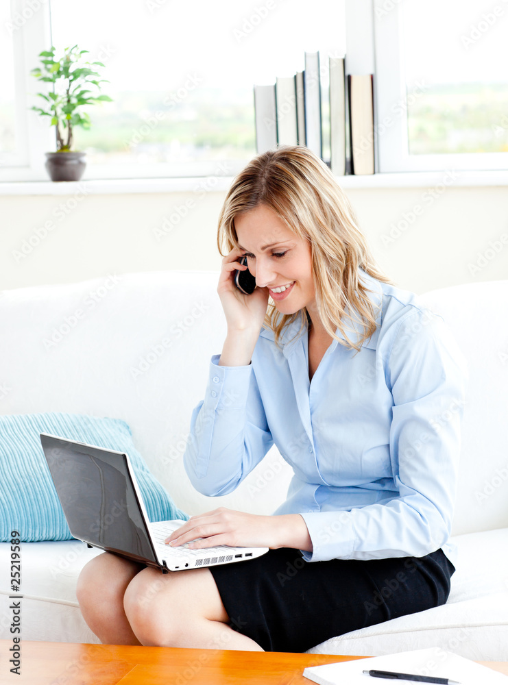 Poster Glowing businesswoman using her phone and laptop in her living-r