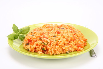 Risotto with tomatoes on a green plate decorated with basil