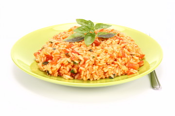 Risotto with tomatoes on a green plate decorated with basil