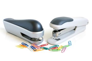 Two staplers and multicolored paper clips