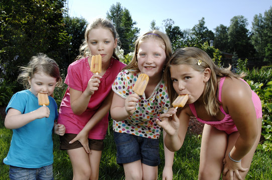 Girls eat popsicle in the backyard