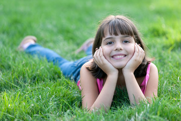 Fototapeta premium Portrait of a dreaming girl in pink on the green grass