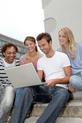 Friends sitting in stairs with laptop computer