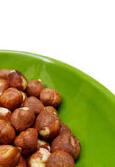 hazelnuts in a green bowl over white