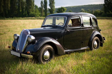 Obraz na płótnie Canvas Beautiful black vintage car in the field.