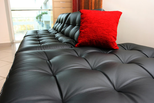 Black leather sofa with a red cushion in office