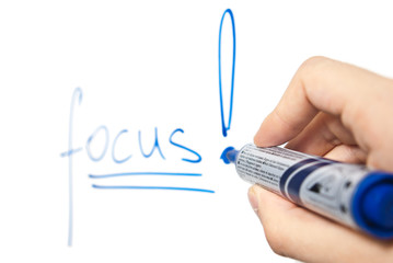 word focus written on whiteboard with selective focus on hand