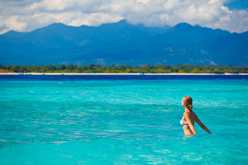 A beautiful woman wearing white bikini facing the sea on a beach