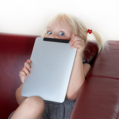 Little blond girl with blue eyes playing  touchpad
