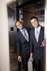 Businessmen in elevator looking out doorway