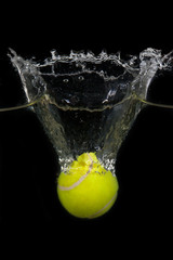 Tennis ball dropped into water on black Background
